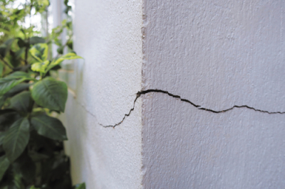 Image of a stucco home with a crack in the wall providing a possible entry point for insects.
